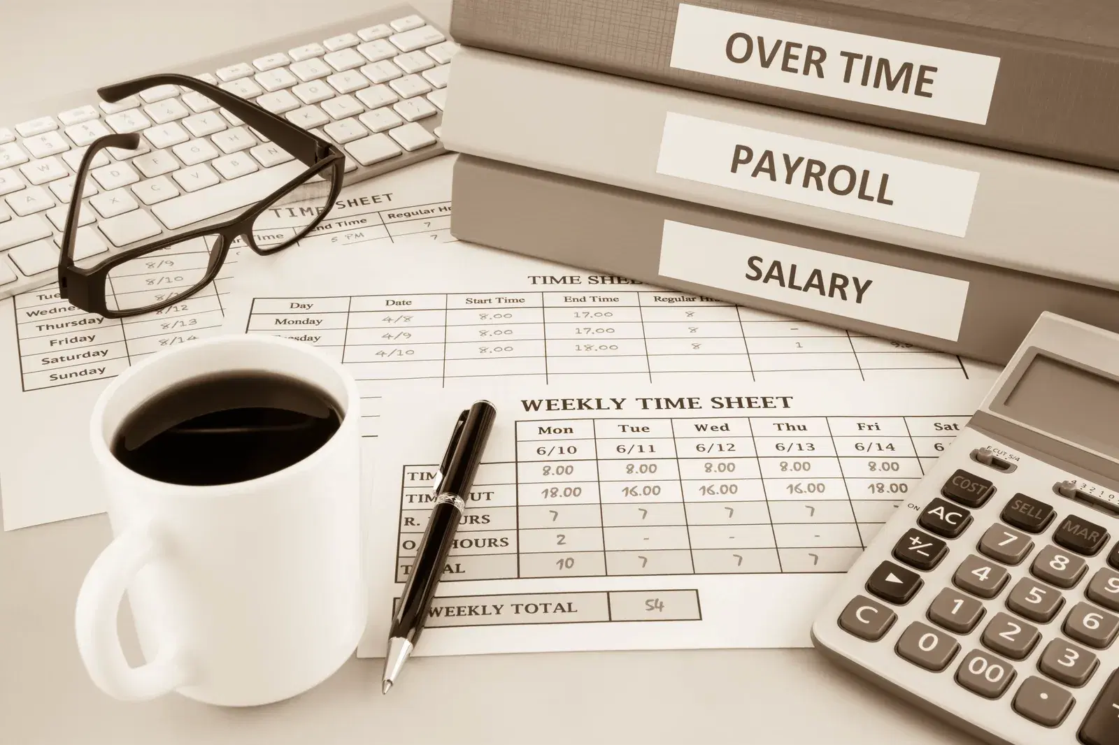 Payroll binders, weekly time sheet, calculator, and coffee on a desk
